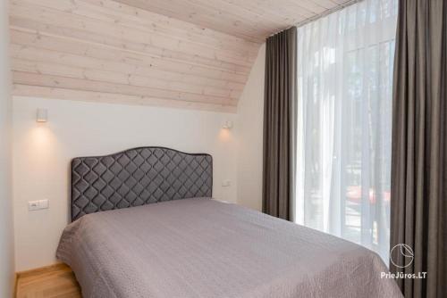 a bedroom with a bed and a large window at Čiki Puki Pajūrys in Palanga