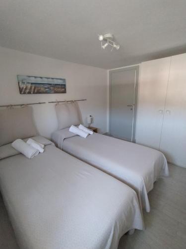 two beds in a hotel room with white sheets at Appartamento Le Ancore in Marciana Marina