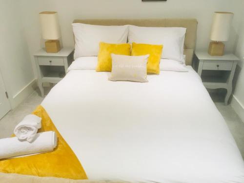 a white bed with yellow pillows and towels on it at Huntingdon Apartment in Huntingdon