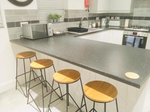a kitchen with a counter and four stools at Huntingdon Apartment in Huntingdon