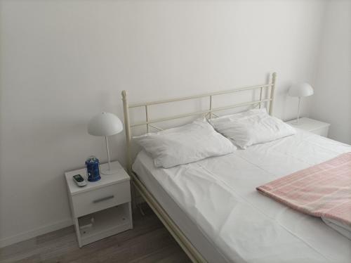 een slaapkamer met een wit bed en een nachtkastje met een lamp bij Vjećna vatra in Sarajevo