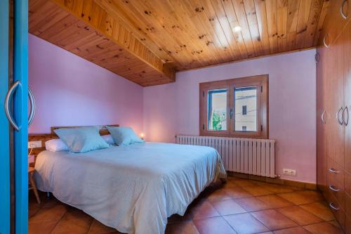 1 dormitorio con cama y techo de madera en Cal Carol, en Vallcebre