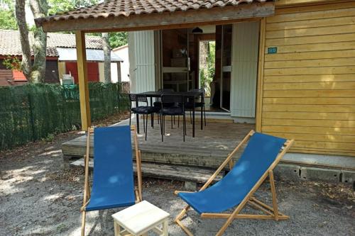 2 Stühle und ein Tisch auf der Veranda eines Hauses in der Unterkunft Cozy chalet des Moussaillons N99 - proche lac in Hourtin