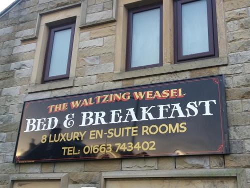 una señal para el bed and breakfast de la comadreja andante en un edificio en The Waltzing Weasel B&B, en Birch Vale