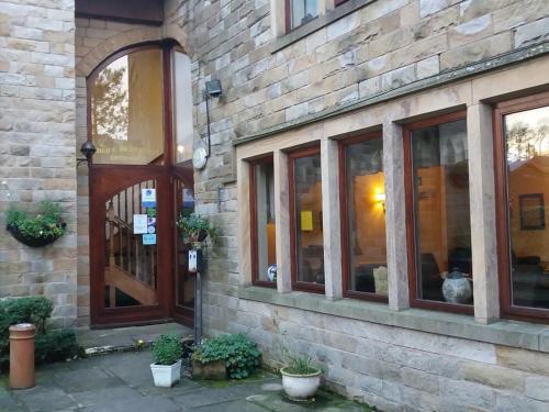 a brick building with a wooden door and windows at The Waltzing Weasel B&B in Birch Vale