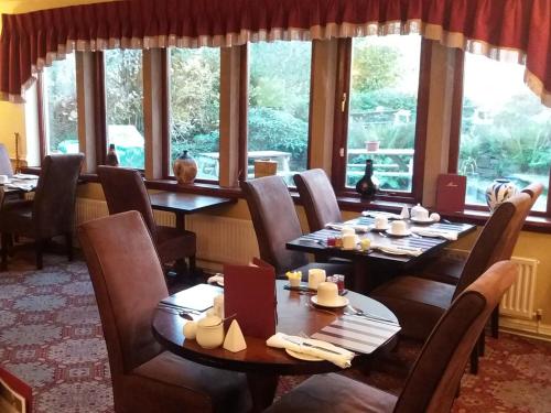 un comedor con mesas, sillas y ventanas en The Waltzing Weasel B&B, en Birch Vale