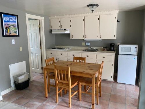 uma cozinha com armários brancos e uma mesa e cadeiras de madeira em Seawinds Motel & Cottages em Digby