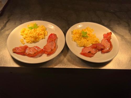 two plates of breakfast food with bacon and eggs at Osborne Hotel in Newcastle upon Tyne