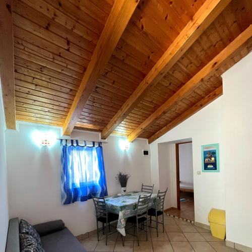 a dining room with a table and chairs and wooden ceilings at Apartmani Lisak Ugrina in Barić Draga