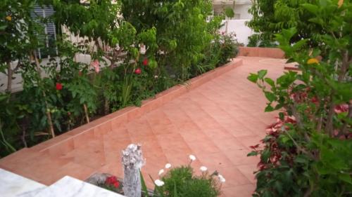 a garden with a brick walkway with flowers and a statue at Elenas Garden in Kavos