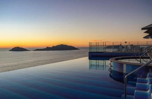 a swimming pool with a view of the ocean at sunset at Central Tower 102 Malecón Mazatlan in Mazatlán