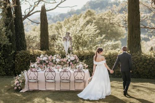 a bride and groom walking past a table with flowers at Relais Sassa al Sole in San Miniato