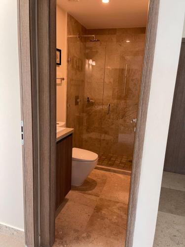 a bathroom with a toilet and a glass shower at Central Tower 102 Malecón Mazatlan in Mazatlán
