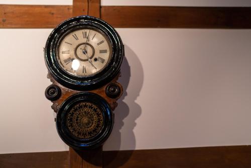 a clock hanging on a wall in a room at Machiya Guest House Carta in Kanazawa