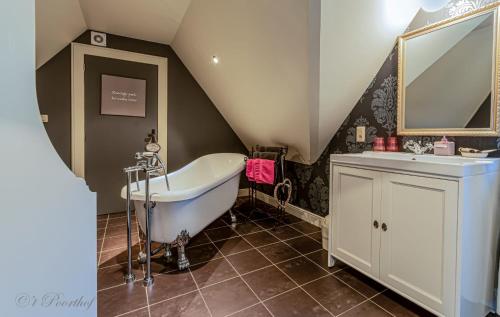 a attic bathroom with a tub and a sink at 't Poorthof in Borgloon