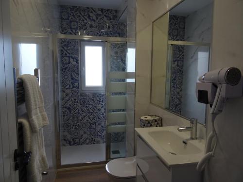uma casa de banho com um lavatório e um chuveiro com um espelho. em LA CASA DE VIOLETA em Suances
