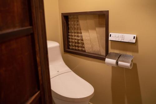 a toilet in a bathroom with a toilet paper dispenser at Machiya Guest House Carta in Kanazawa