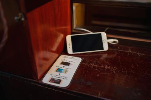 a cell phone sitting on top of a wooden table at Machiya Guest House Carta in Kanazawa