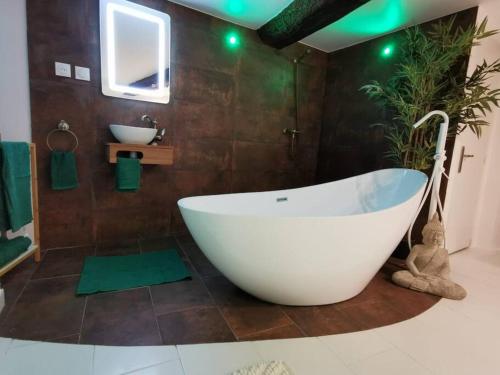 un bagno con ampia vasca bianca e lavandino di Studio équipé avec Lit rond / baignoire ilot / Table massage Aux Arcs a Les Arcs-sur-Argens
