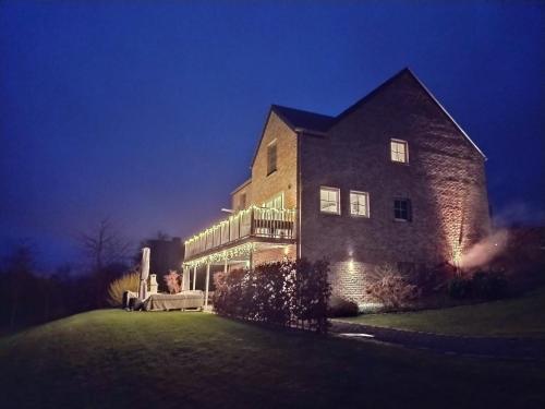 a large brick house with lights on it at night at B&B Maison Durbois in Durbuy