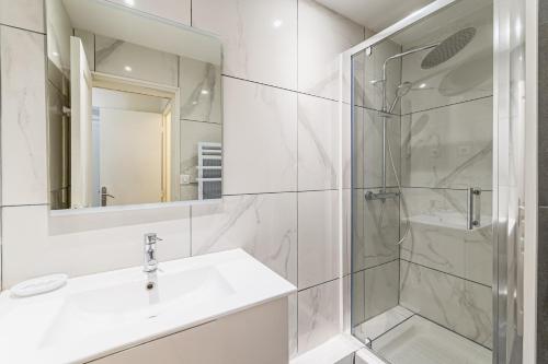 La salle de bains blanche est pourvue d'un lavabo et d'une douche. dans l'établissement MICHELET: T2 avec parking à 10 min des Plages, à Marseille