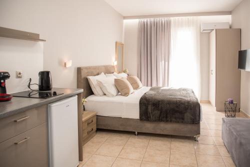 a bedroom with a bed and a kitchen with a window at Avyssos Residents in Kalamaki