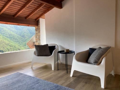 two chairs and a table in a room with a large window at house in the medieval village in Apricale