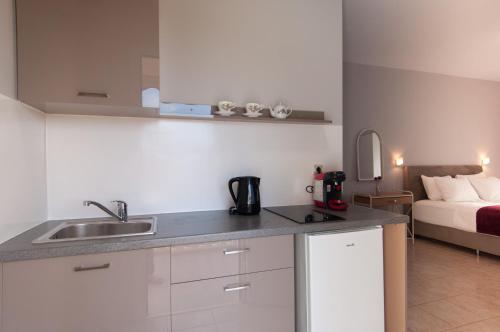 a kitchen with a sink and a room with a bed at Avyssos Residents in Kalamaki
