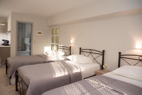 a bedroom with three beds with white sheets at Avyssos Residents in Kalamaki