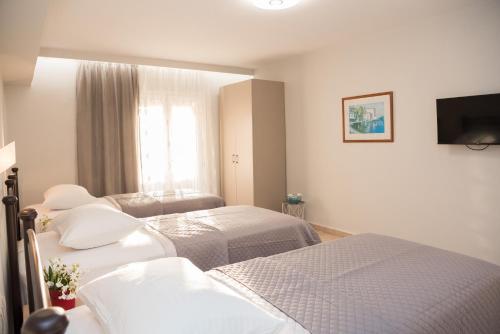 a hotel room with two beds and a flat screen tv at Avyssos Residents in Kalamaki