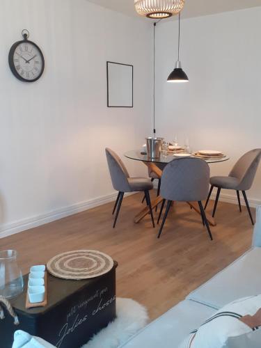 a dining room with a table and chairs and a clock at L' atelier du 26 in Dinan