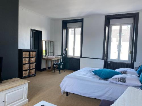 um quarto com uma cama, uma secretária e janelas em CHAMBRE SPACIEUSE DANS MAISON RENOVEE em Granville