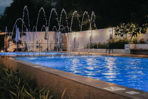 a swimming pool with a fountain at night at Urban Oasis Resort, Tarlac in Tarlac