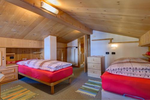 two beds in a room with wooden ceilings at Bait da Marieta in Livigno