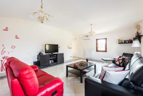 a living room with a red leather couch and a tv at Casa delle Noci country house, pool & SPA in Modena