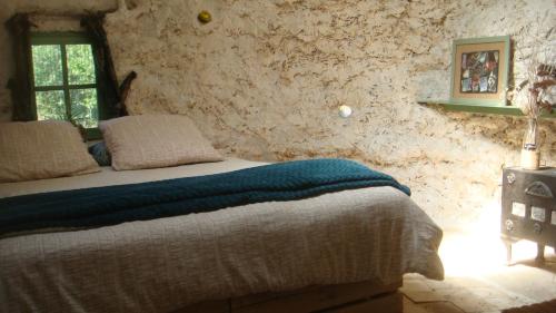 um quarto com uma cama numa parede de pedra em Kerterre des Gallerands em Bessais-le-Fromental