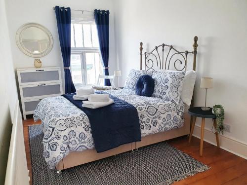 a bedroom with a bed with blue and white sheets and a window at Coastal escape in the heart of Saltburn in Saltburn-by-the-Sea