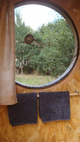 uma janela redonda com duas toalhas num piso de madeira em Kerterre des Gallerands em Bessais-le-Fromental
