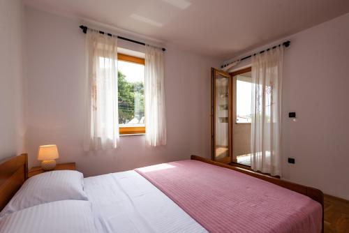 a bedroom with a large bed and two windows at Apartments Smiljanic in Tribunj
