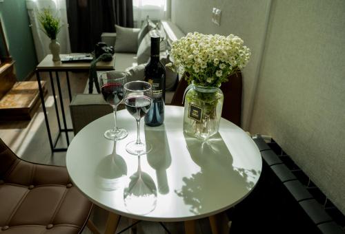 a table with two glasses and a bottle of wine and flowers at Luxury Duplex Suites - City Center in Tbilisi City