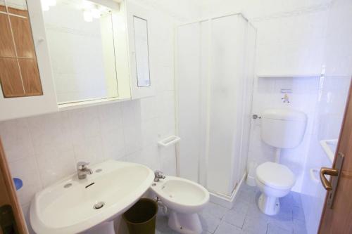 a white bathroom with a sink and a toilet at Villa Conti Residence in Lacona