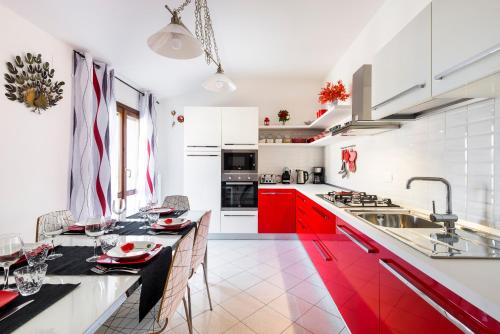 a kitchen with red cabinets and a dining table at Casa delle Noci country house, pool & SPA in Modena
