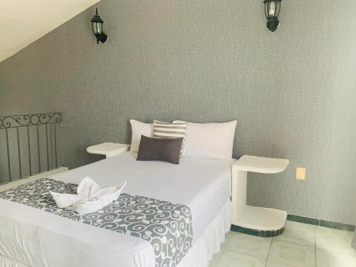 a bedroom with a white bed and a chair at Hotel & Suites Bausan in Boca del Río