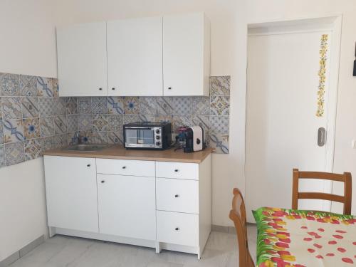 une cuisine avec des placards blancs et un four micro-ondes sur un comptoir dans l'établissement Casa del Limone, à Santa Maria Del Focallo