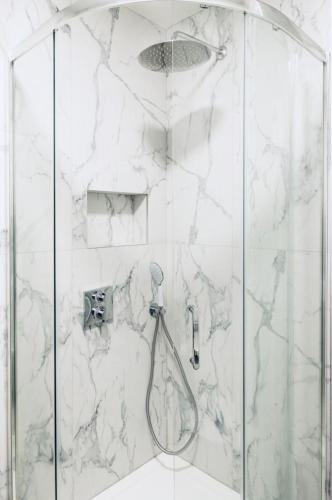 a bathroom with a shower with white marble walls at ADIRAMA Apartments Elegant Apartments Walk to the Beach in Obzor