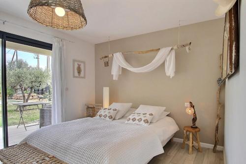 a bedroom with a bed with white sheets and a window at La Villa Aux Oliviers in Flayosc
