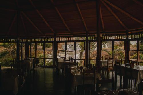 uma sala de jantar com mesas, cadeiras e janelas em Hotel Vale do Jiquiriçá em Jiquiriçá