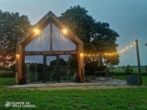 a tent with lights and a table in a field at Mazurskie Stodoły in Piecki