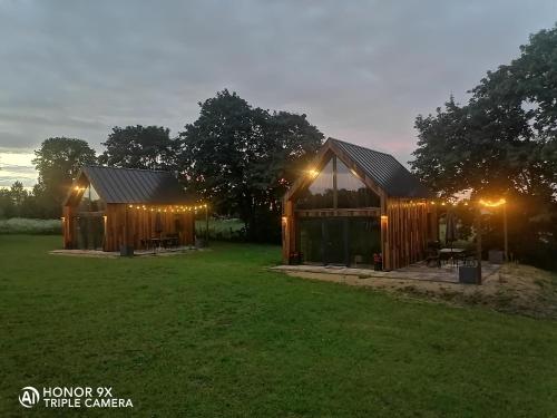 a couple of wooden buildings with lights on them at Mazurskie Stodoły in Piecki