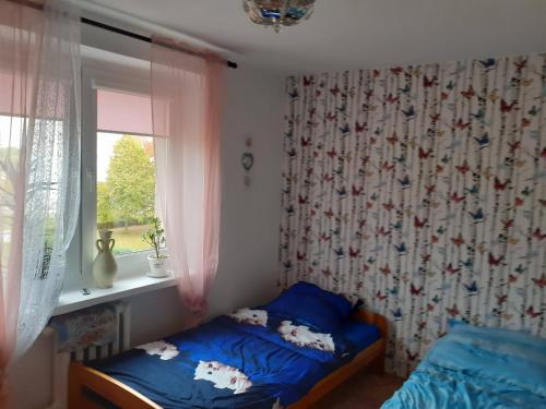 1 dormitorio con cama con sábanas azules y ventana en APARTAMENT LAZUROWY en Władysławowo